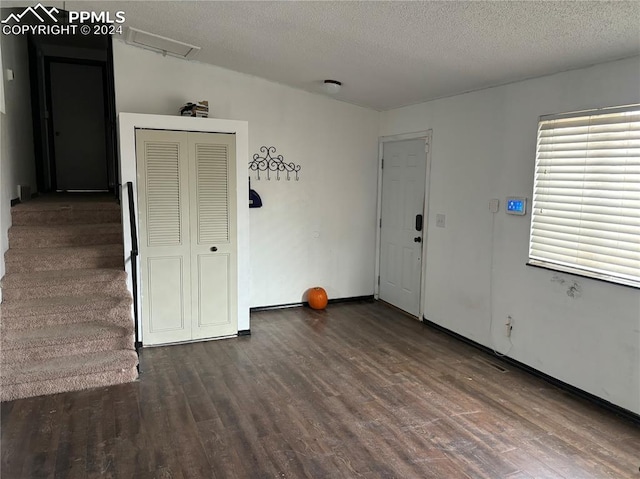 empty room with a textured ceiling and dark wood-type flooring