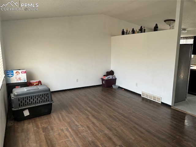 unfurnished room with lofted ceiling and dark wood-type flooring