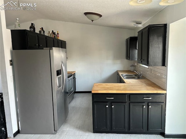 kitchen featuring sink, wood counters, backsplash, a textured ceiling, and appliances with stainless steel finishes