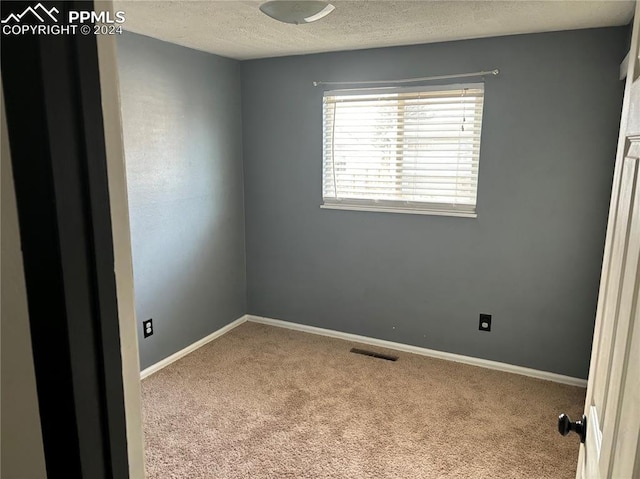 carpeted spare room featuring a textured ceiling