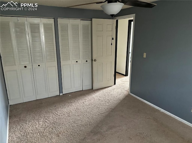 unfurnished bedroom with ceiling fan, carpet, and two closets