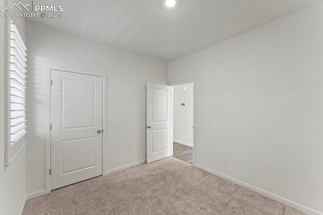 unfurnished bedroom featuring light carpet and multiple windows