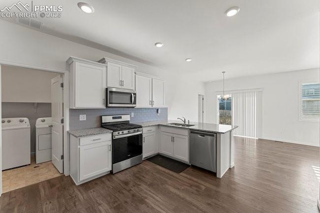 kitchen with white cabinets, stainless steel appliances, washing machine and clothes dryer, sink, and kitchen peninsula