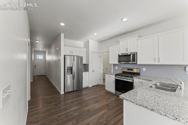 kitchen with dark hardwood / wood-style floors, sink, stainless steel appliances, white cabinets, and light stone counters