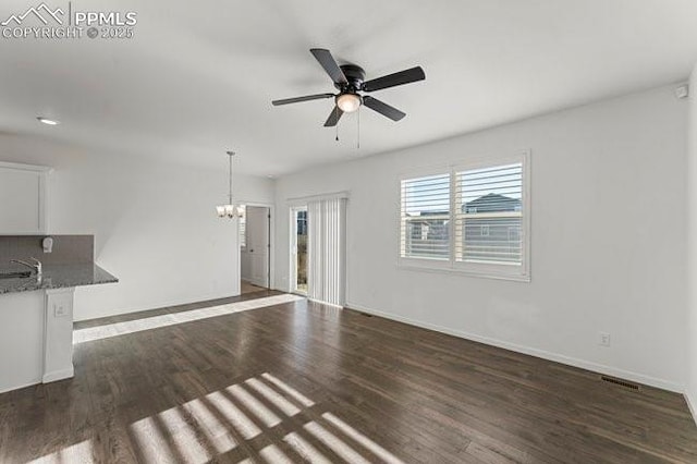 unfurnished living room with dark hardwood / wood-style flooring, ceiling fan with notable chandelier, and sink