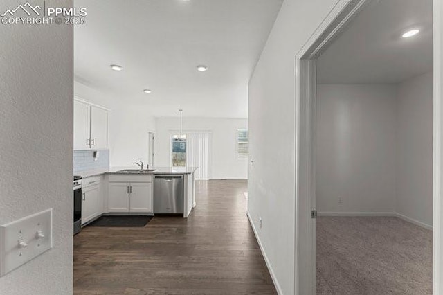 kitchen with kitchen peninsula, appliances with stainless steel finishes, pendant lighting, white cabinets, and sink