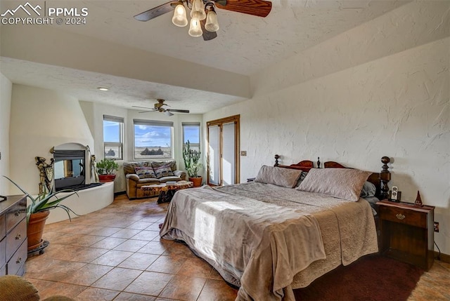 bedroom featuring ceiling fan, tile patterned flooring, and a textured ceiling