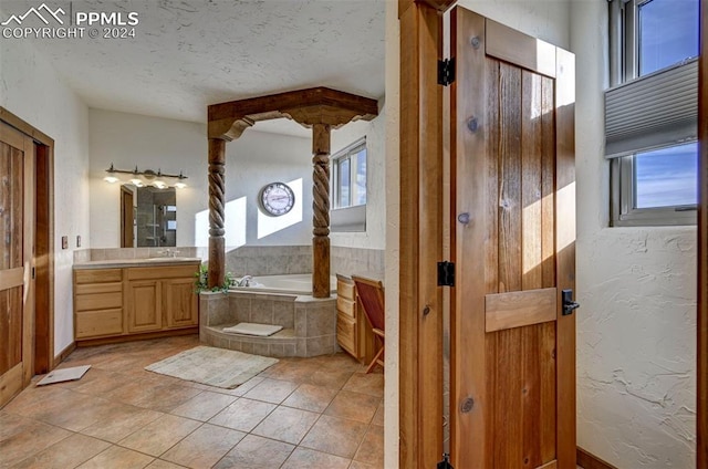 bathroom with tile patterned floors, tiled bath, a wealth of natural light, and vanity