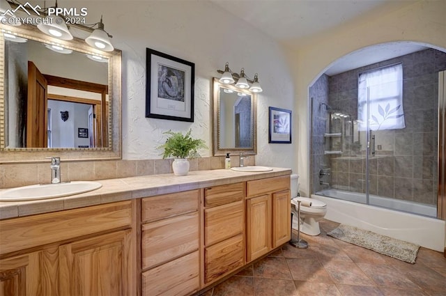 full bathroom with tile patterned floors, vanity, toilet, and bath / shower combo with glass door