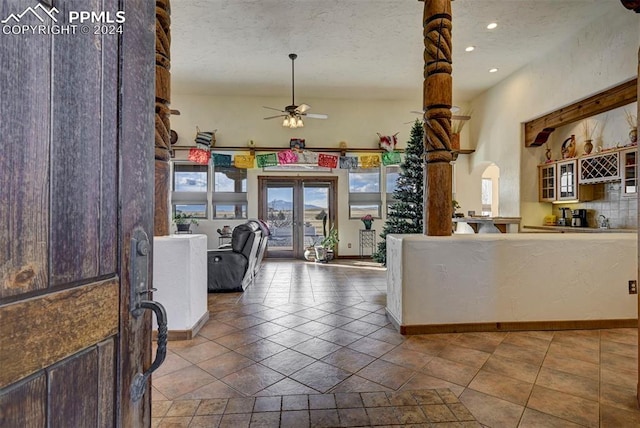 interior space featuring ceiling fan, french doors, a textured ceiling, and tile patterned flooring