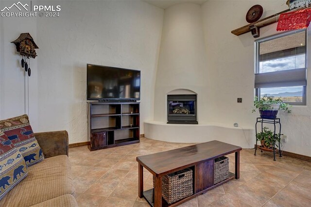 living room with a fireplace, light tile patterned floors, and a high ceiling