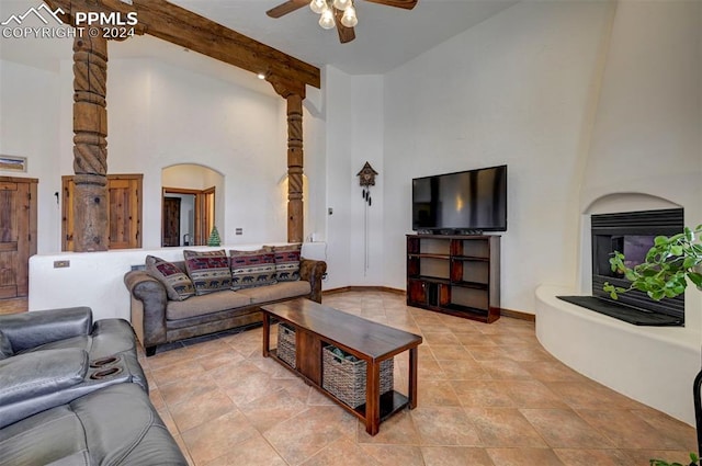 living room featuring beam ceiling, ceiling fan, a large fireplace, and high vaulted ceiling