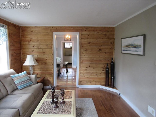 living room with wooden walls, hardwood / wood-style floors, and ornamental molding