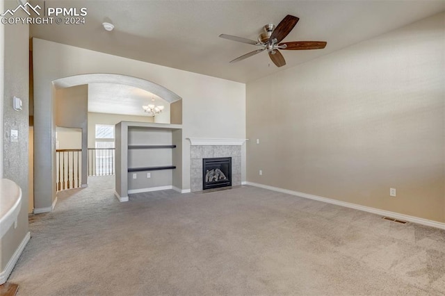 unfurnished living room featuring light carpet, ceiling fan with notable chandelier, and a fireplace