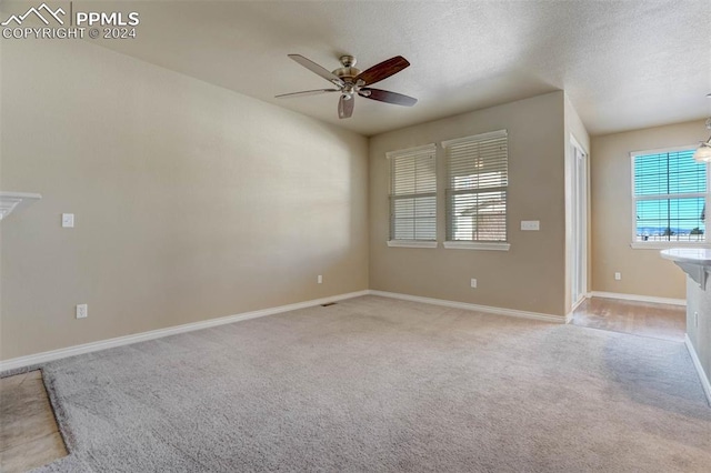 unfurnished room with ceiling fan, light colored carpet, and a textured ceiling