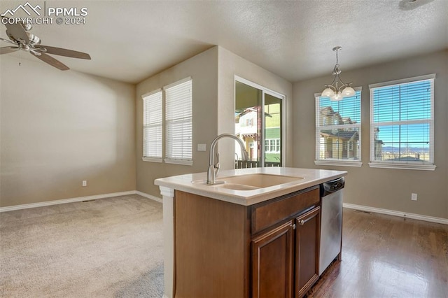 kitchen with pendant lighting, dishwasher, a center island with sink, ceiling fan with notable chandelier, and sink