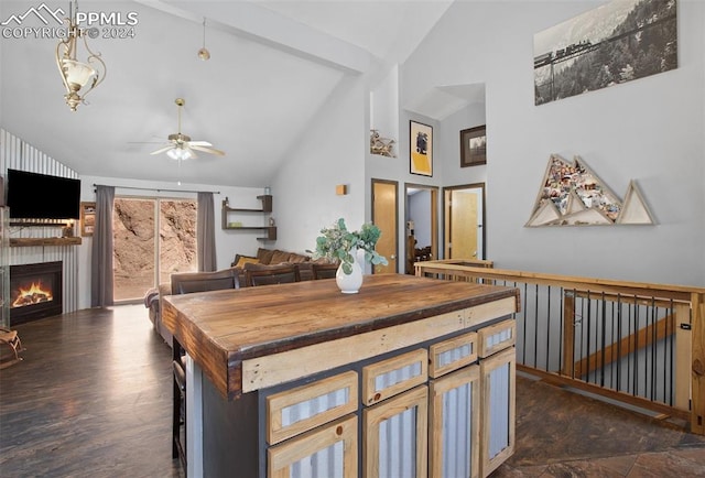 interior space featuring high vaulted ceiling, a fireplace, beamed ceiling, ceiling fan, and dark wood-type flooring