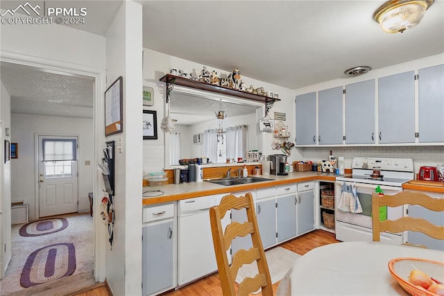 kitchen featuring sink, light hardwood / wood-style floors, a textured ceiling, white appliances, and decorative backsplash