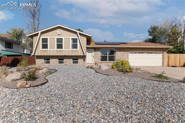 split level home featuring solar panels and a garage