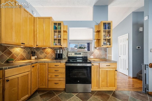 kitchen featuring tile counters, dark wood-type flooring, backsplash, a textured ceiling, and stainless steel range with electric cooktop