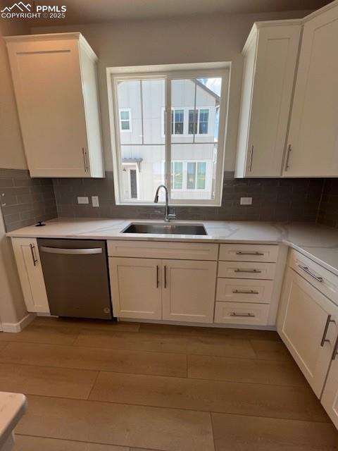 7010 Knapp Dr, Colorado Springs, CO 80924 - kitchen with stainless steel dishwasher, light wood finished floors, white cabinets, and light countertops