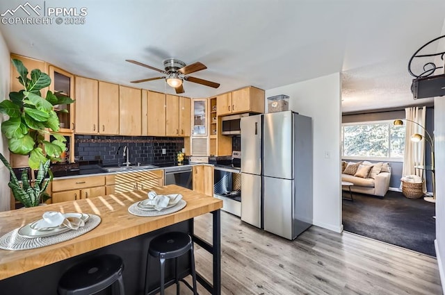 kitchen featuring wood counters, sink, light brown cabinets, stainless steel appliances, and decorative backsplash