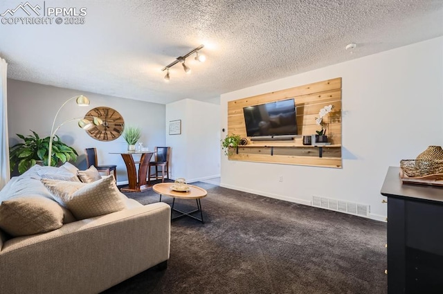 living room featuring dark carpet, track lighting, and a textured ceiling