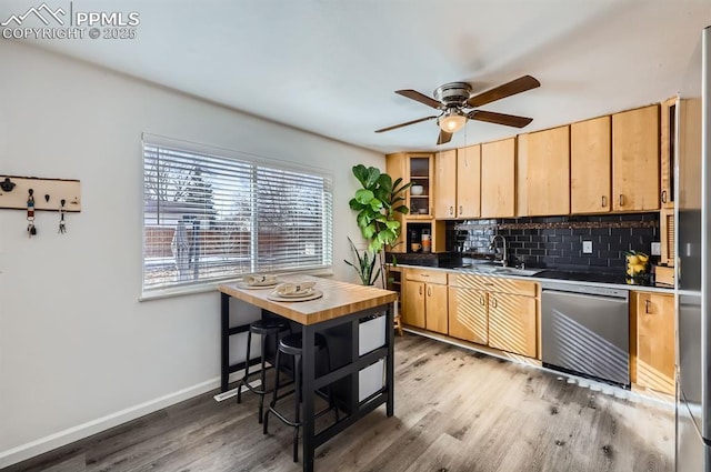 kitchen featuring light wood-type flooring, dishwasher, sink, and backsplash