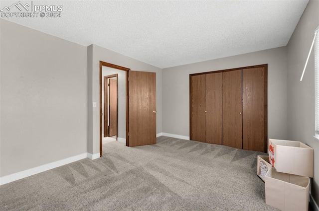 unfurnished bedroom featuring a closet, light colored carpet, and a textured ceiling