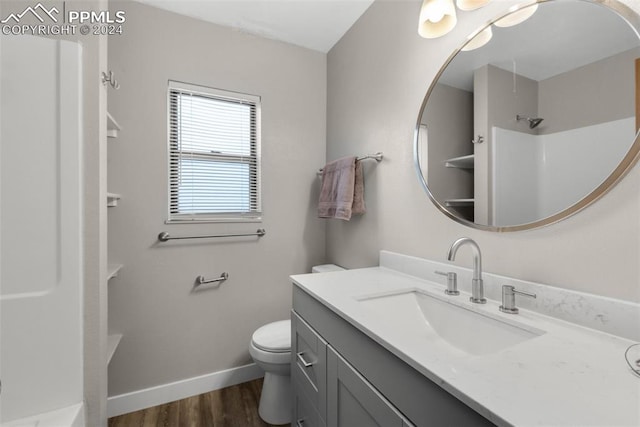 bathroom featuring a shower, hardwood / wood-style floors, vanity, and toilet