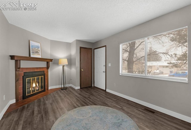 living area with a fireplace, a textured ceiling, and dark wood-type flooring