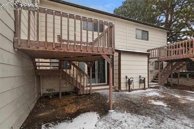 snow covered back of property featuring a wooden deck