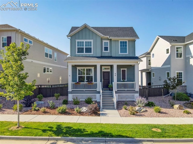 view of front of home featuring a porch, board and batten siding, and fence