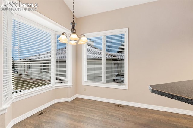 unfurnished dining area featuring a chandelier and wood-type flooring