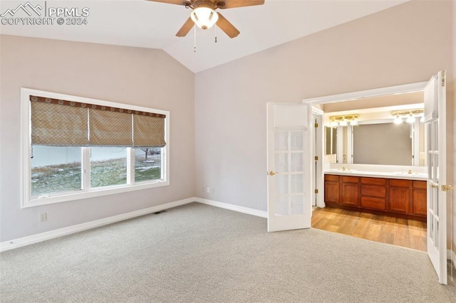 unfurnished bedroom featuring french doors, light colored carpet, ceiling fan, connected bathroom, and lofted ceiling