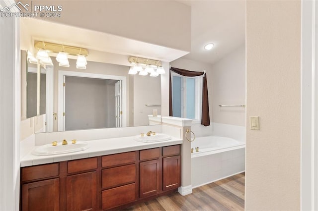 bathroom featuring tiled bath, vanity, and hardwood / wood-style flooring