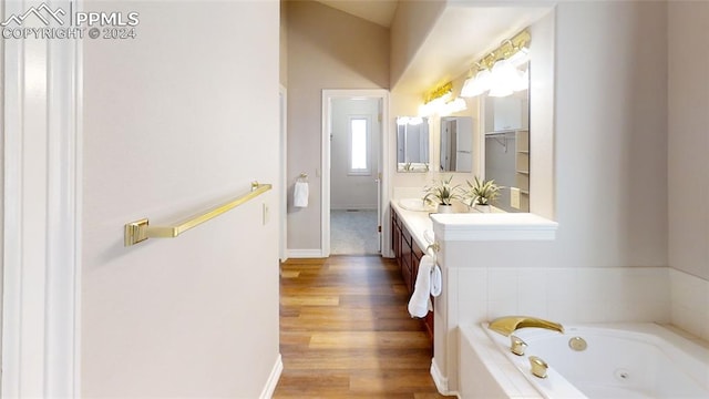 bathroom featuring tiled tub, vanity, and wood-type flooring