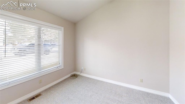 carpeted spare room with lofted ceiling