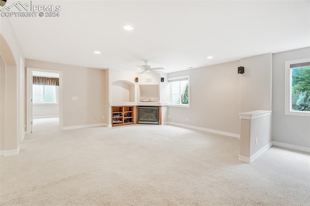 unfurnished living room with plenty of natural light, ceiling fan, and light colored carpet