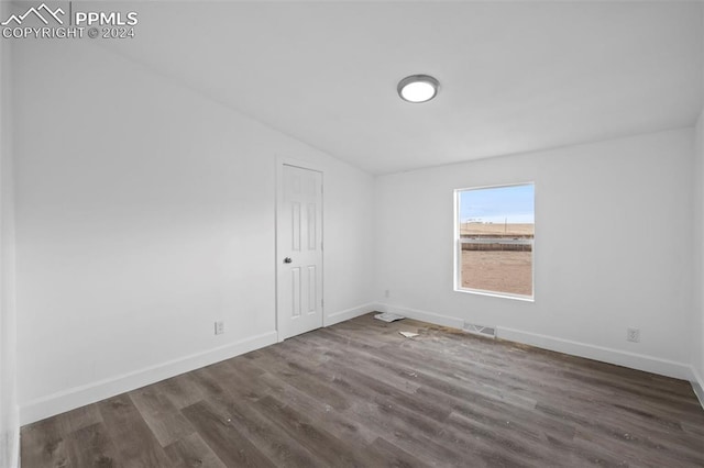 spare room featuring lofted ceiling and dark wood-type flooring