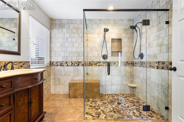 bathroom with tile patterned floors, a shower with door, vanity, and tile walls