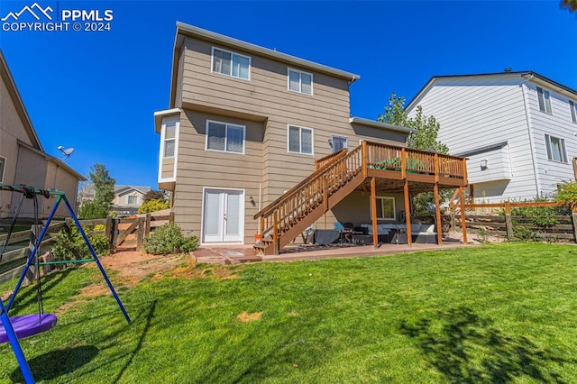 back of house featuring a lawn, a patio area, a playground, and a wooden deck