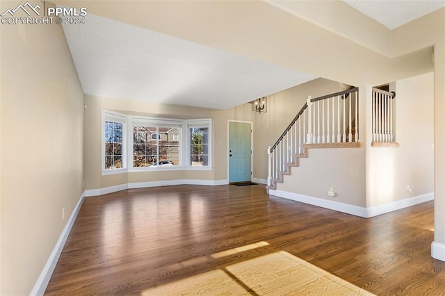 unfurnished living room with hardwood / wood-style flooring and a notable chandelier