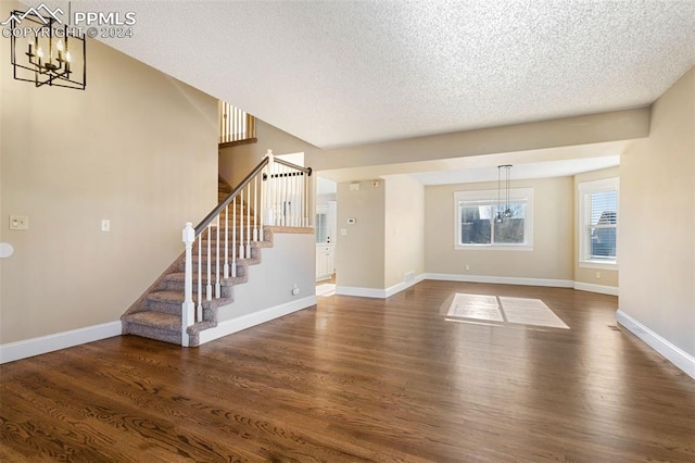 unfurnished living room with a textured ceiling, a chandelier, and dark hardwood / wood-style floors