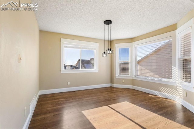 unfurnished dining area featuring dark hardwood / wood-style flooring and a textured ceiling