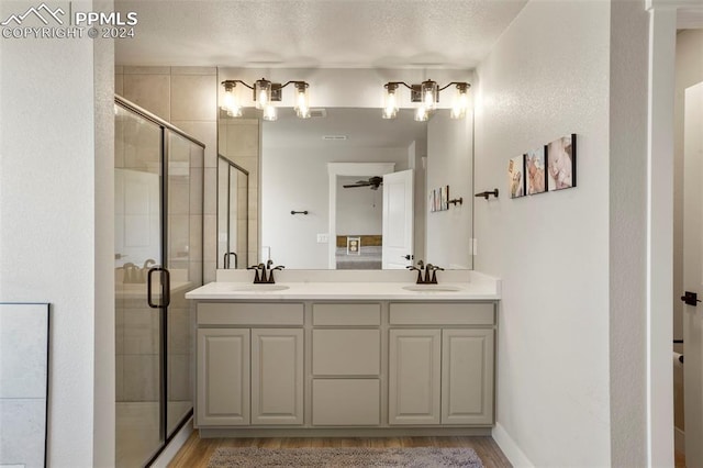 bathroom featuring vanity, wood-type flooring, a textured ceiling, and a shower with door