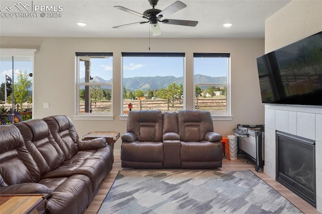 living room featuring ceiling fan, light hardwood / wood-style floors, and a fireplace