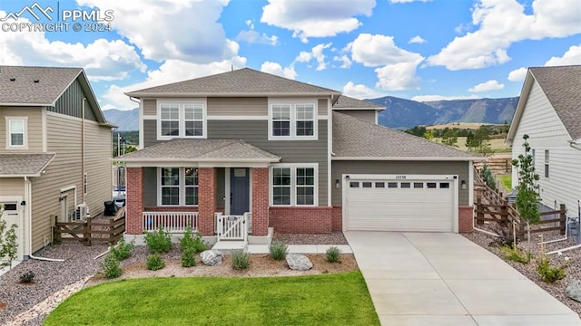 view of front facade with a mountain view, a porch, a garage, and a front lawn