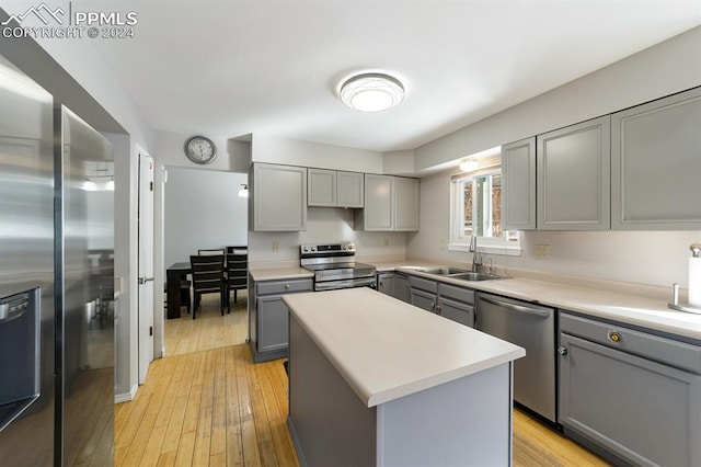 kitchen with gray cabinetry, a kitchen island, sink, and appliances with stainless steel finishes