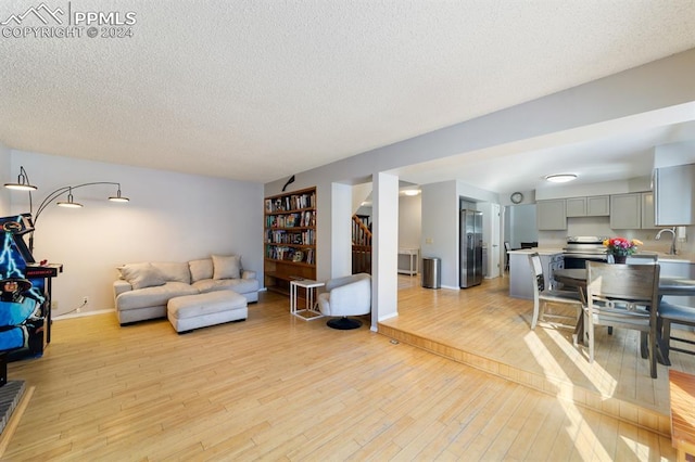 living room featuring a textured ceiling, light wood-type flooring, and sink